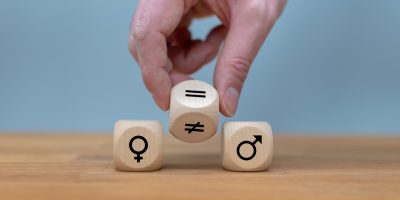 Symbol for gender equality. Hand turns a dice and changes a unequal sign to a equal sign between symbols of men and women.