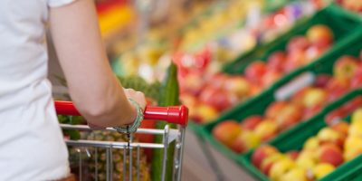 Cropped image of young woman pushing shopping cart in grocery store