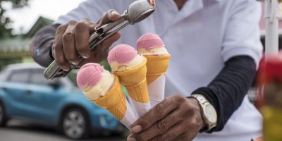 A Sorbetero scoops strawberry and cheese sorbetes into in small wafer cones. Traditional ice cream in the Philippines.