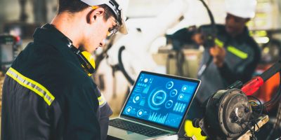 Young factory worker working with adept robotic arm in a workshop . Industry robot programming software for automated manufacturing technology .