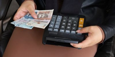 hands of a woman holding colombian banknotes and a calculator